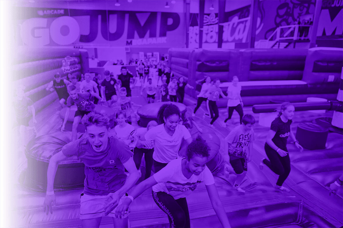 A busy session at a GoJump park, children running across the inflatable arena floor